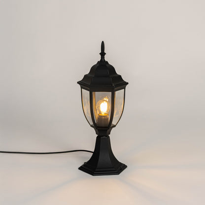 Black metal outdoor gate light with glowing bulb and clear glass shade for modern decor use.