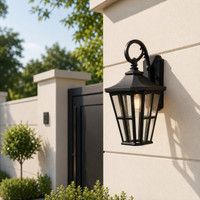 Vintage black iron scroll arm tapered cage glass wall lantern fixture on stone pillar for outdoor home entryway lighting.