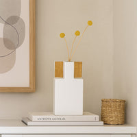 Modern white ceramic vase with gold accents displayed on a clean minimal surface  styled in soft lighting for a refined contemporary look.