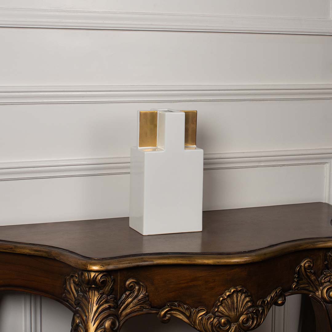 Sleek white ceramic vase featuring bold gold detailing  photographed against a clean white background to highlight its modern design.
