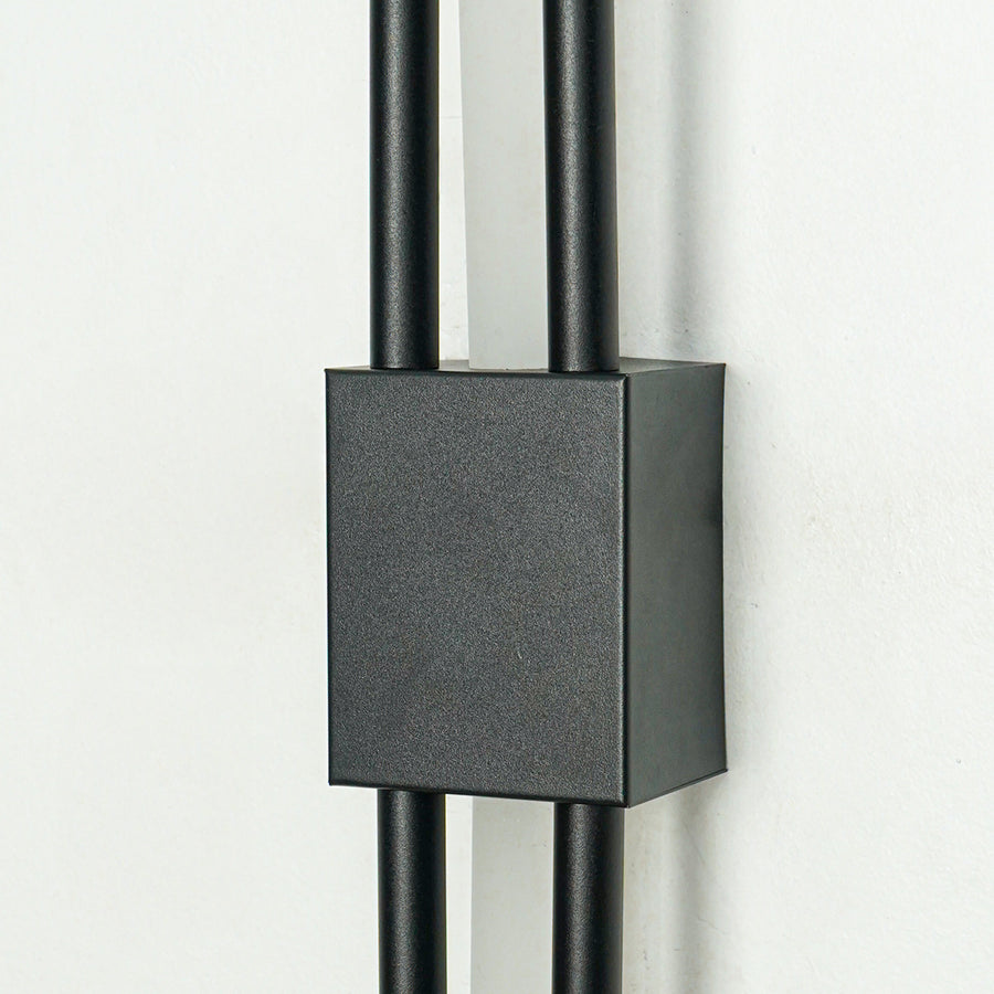 Closeup of textured black metal wall light with sleek dual rods for luxury hallway bedroom and living room interiors.