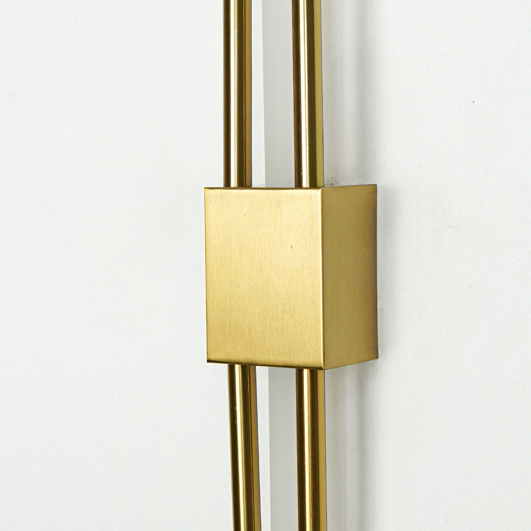 Closeup of brushed gold metal wall light with sleek dual rod design for luxury modern home interior decor.