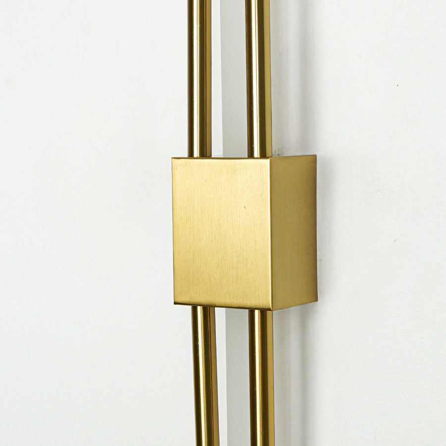 Closeup of brushed gold metal wall light with sleek dual rod design for luxury modern home interior decor.