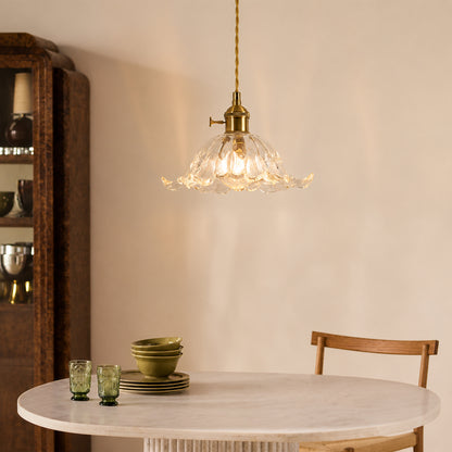 Brass metal and clear glass pendant light adding warm elegance above the dining table in interiors.