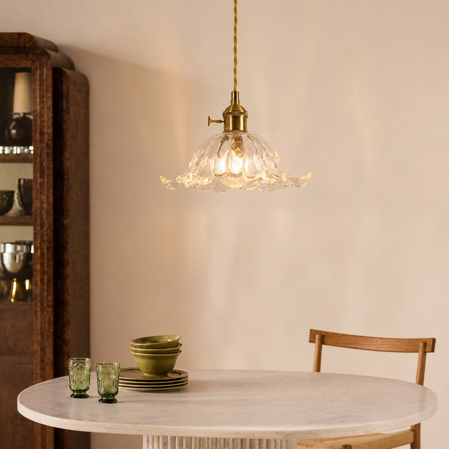 Brass metal and clear glass pendant light adding warm elegance above the dining table in interiors.