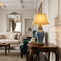 Table lamp with ceramic base and fabric shade placed on wooden side table adding warm ambient lighting to elegant living room decor.