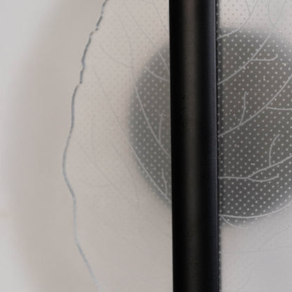 Closeup of black wall light with leaf shaped acrylic acrylic shade highlighting textured leaf pattern and sleek finish.