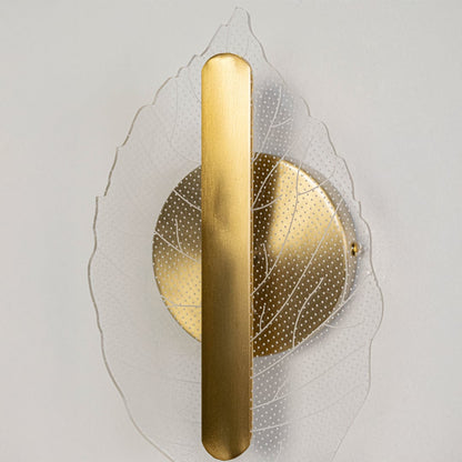 Closeup of gold metal and clear textured glass leaf wall light showing fine detailing for modern decorative home lighting.