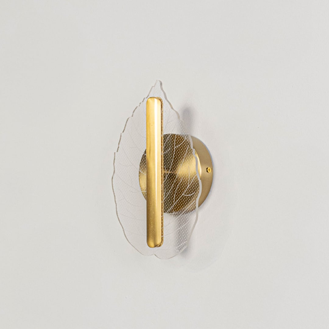 Gold metal and clear glass leaf wall light displayed off on a white background showing its elegant modern home decor finish.