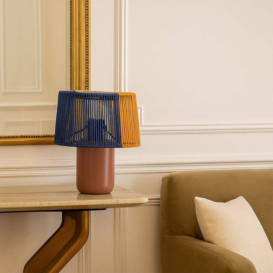 Decorative table lamp with blue and mustard woven shade placed near an armchair adding warm accent lighting to an elegant living space