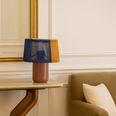 Decorative table lamp with blue and mustard woven shade placed near an armchair adding warm accent lighting to an elegant living space