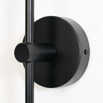 Closeup of modern black wall sconce with cylindrical glass shade sleek metal finish perfect for bedroom living room and hallway.