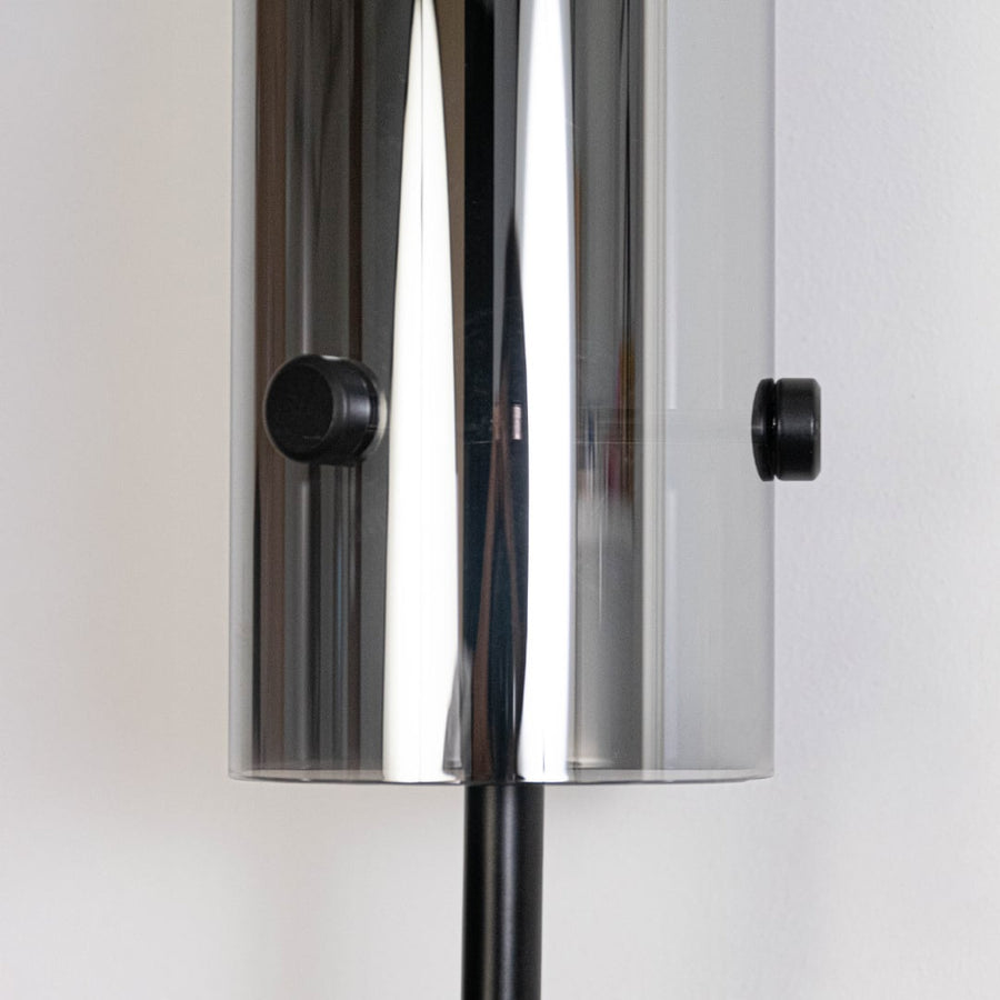 Detailed closeup of gold wall sconce with cylindrical glass shade elegant slim design ideal for modern interiors and luxury décor.