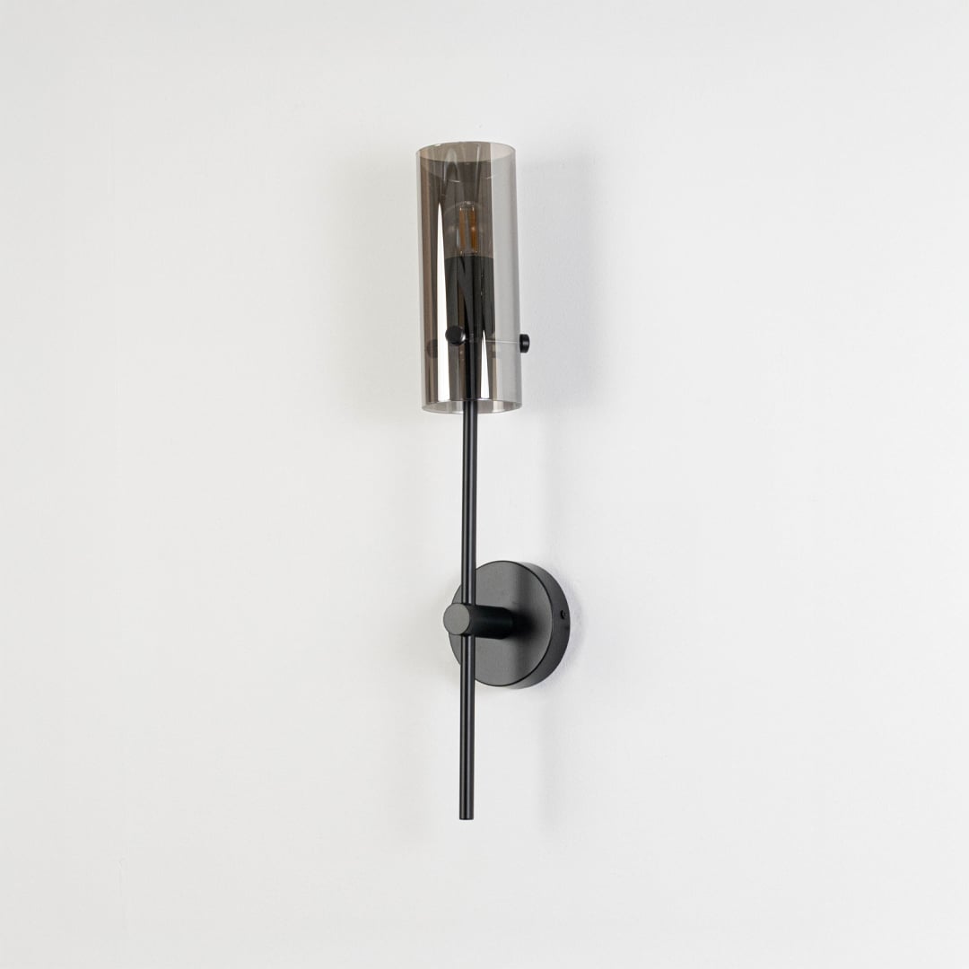 Minimalist black wall sconce with cylindrical glass shade shown switched off against plain white background for product display.