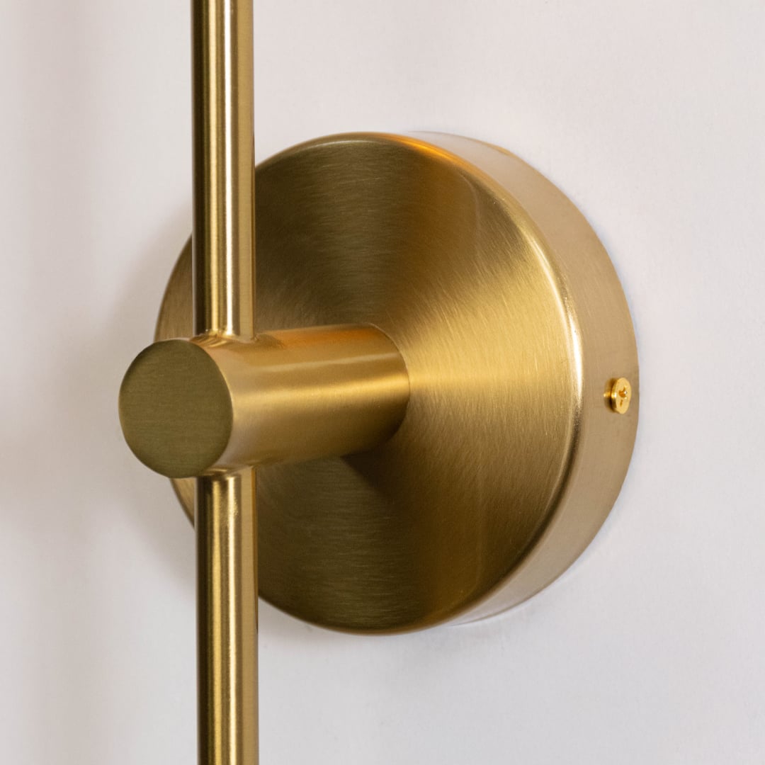 Closeup of modern gold wall sconce with clear glass shade and sleek cylindrical design perfect for living room or bedroom.