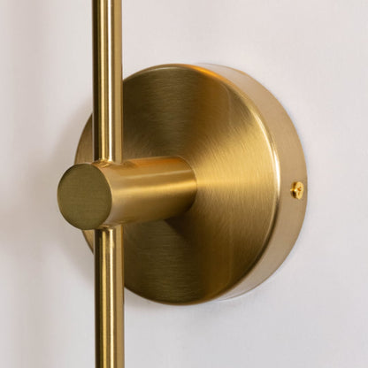 Closeup of modern gold wall sconce with clear glass shade and sleek cylindrical design perfect for living room or bedroom.