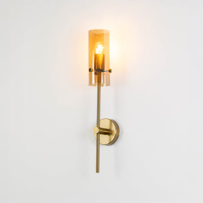 Minimal wall light in gold metal finish with cylindrical glass shade for bedroom or living room decor lighting white background.