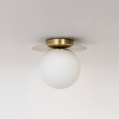 Ceiling light with brushed gold finish base and frosted glass globe shade shown off on plain white background.