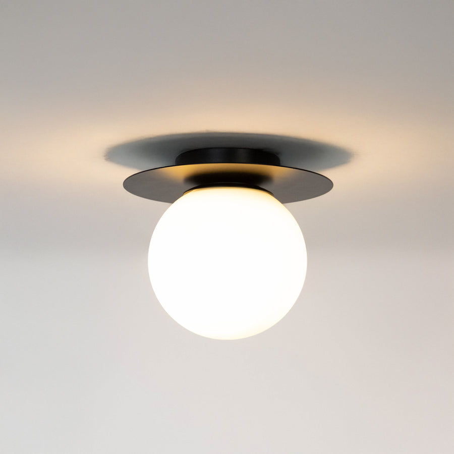 Modern black metal ceiling light with frosted white glass globe for contemporary bedroom and elegant decor styling spaces.