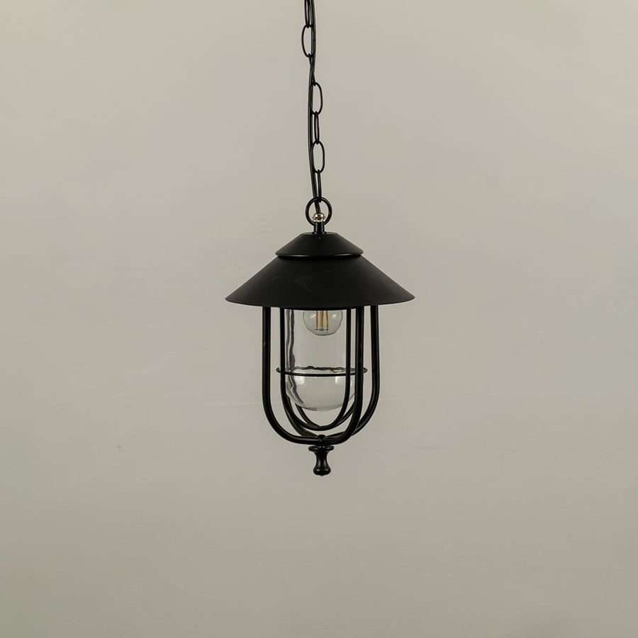 Outdoor hanging lantern with light off shown on a white background featuring a clear glass body and sleek metal frame with smooth detailing.