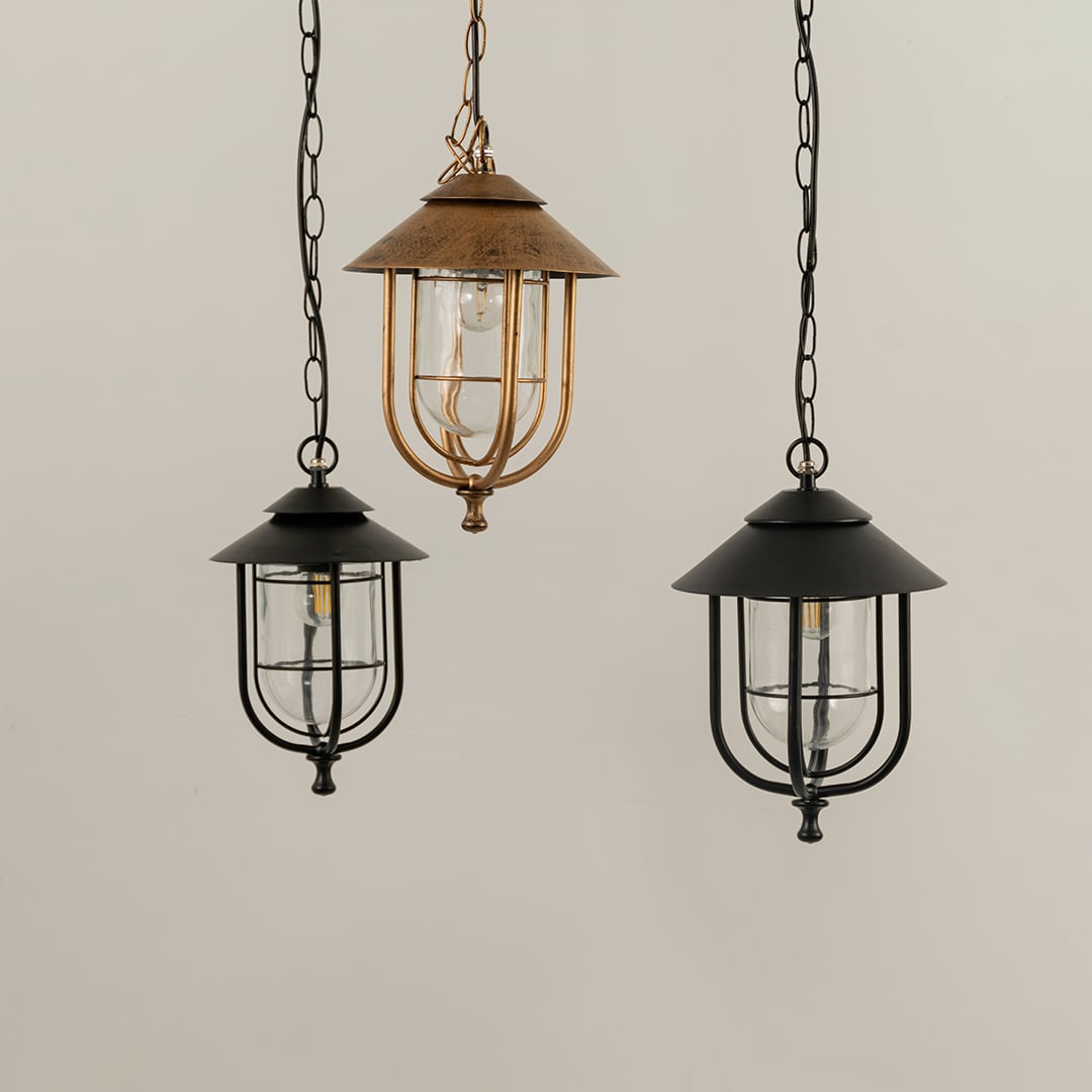 Three lanterns arranged side by side with the lights off emphasizing their distinct frame designs clear glass panels and decorative craftsmanship.
