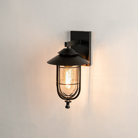 ndustrial black metal outdoor wall sconce on white background with a clear glass cage lantern for hallway decor.