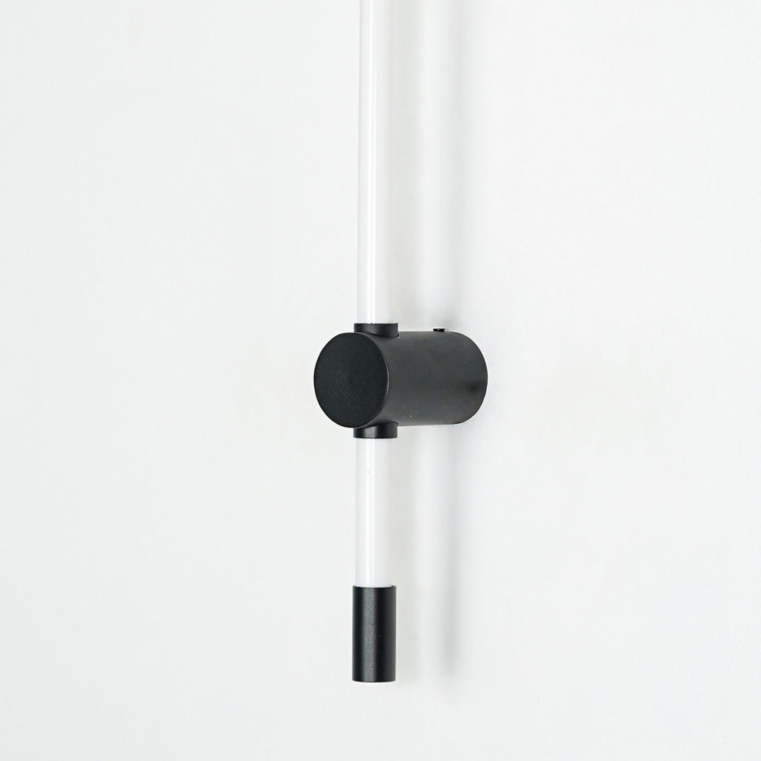 Closeup of wall light with cylindrical black mount and dual tube structure showcasing sleek finish for modern interior decor styling.