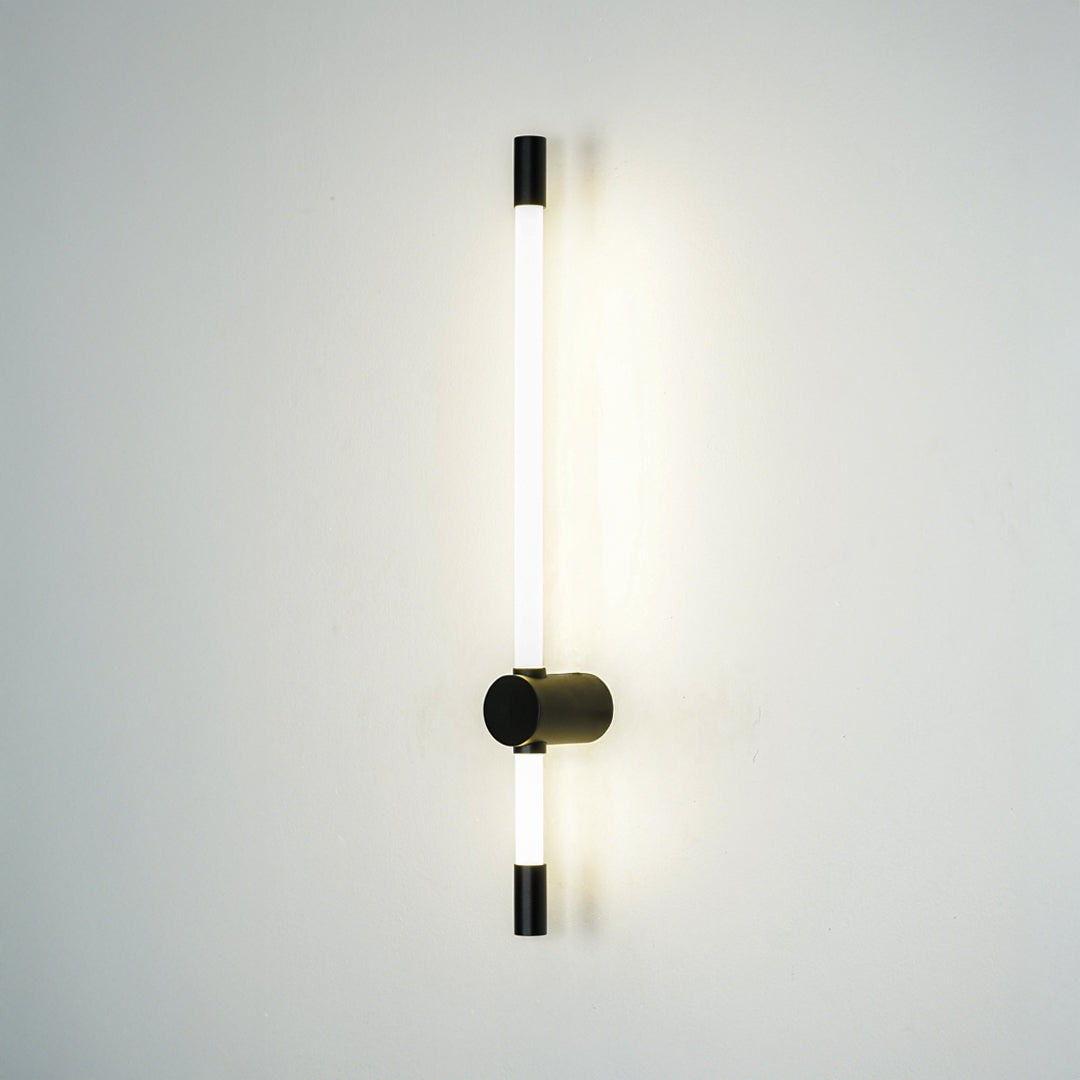 Minimal wall light with vertical tube and black mount emitting soft ambient glow perfect for hallway or bedroom wall decor placement.