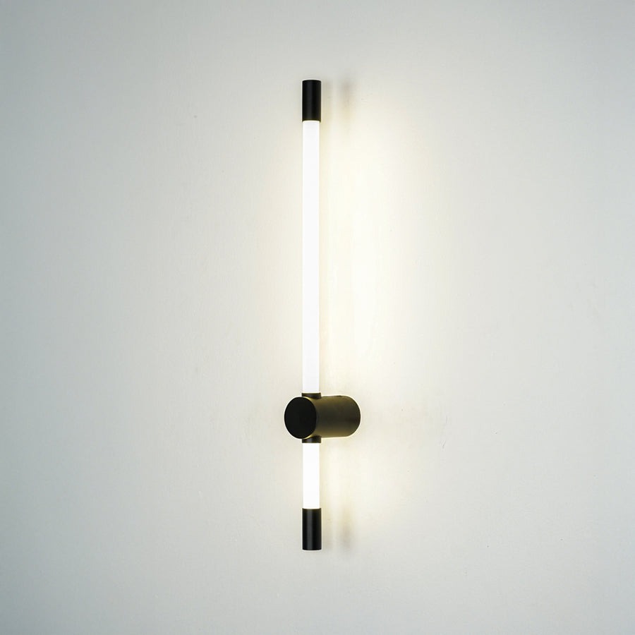 Minimal wall light with vertical tube and black mount emitting soft ambient glow perfect for hallway or bedroom wall decor placement.