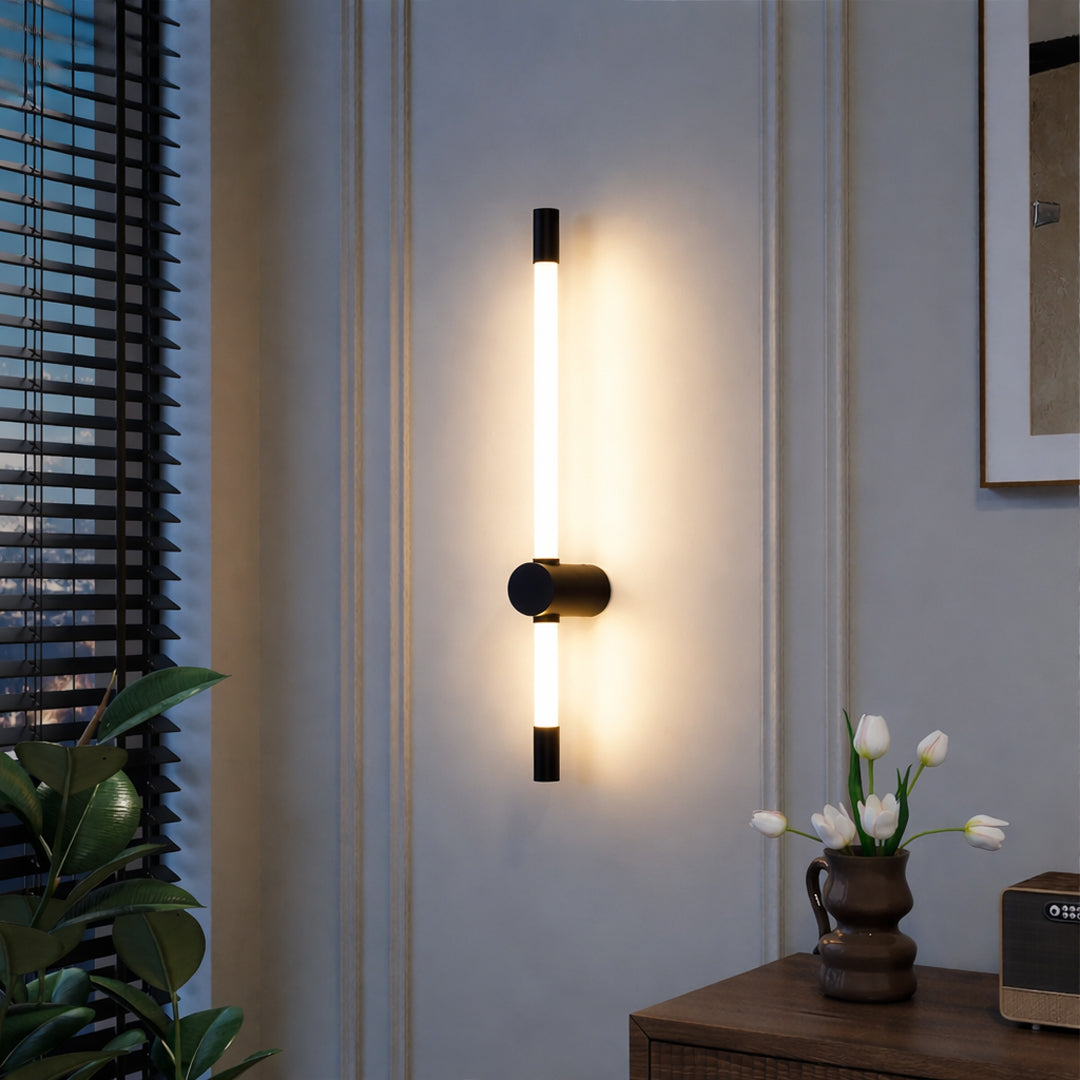 Modern wall light with vertical tube design and black metal mount emitting warm glow ideal for bedroom or living room wall decor.