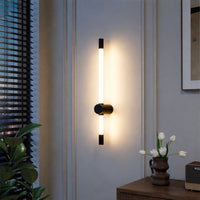 Modern wall light with vertical tube design and black metal mount emitting warm glow ideal for bedroom or living room wall decor.