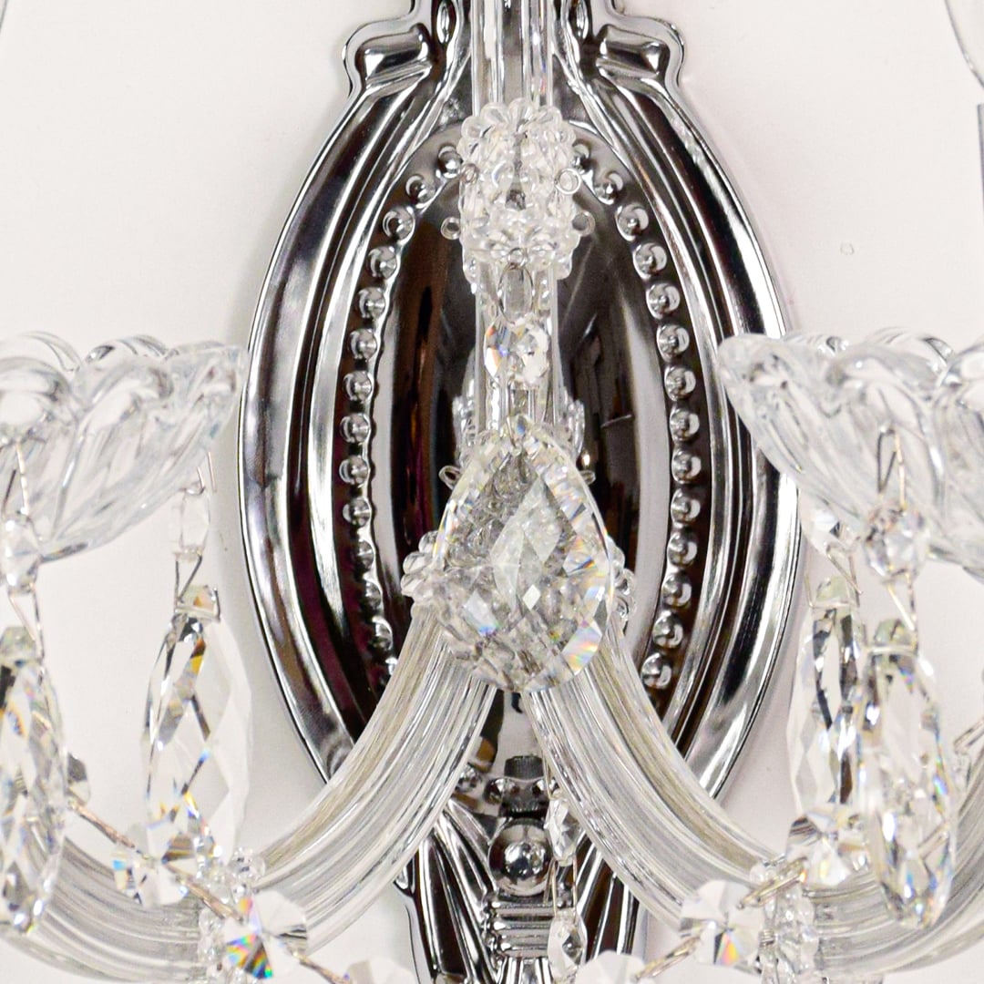 Closeup of silver crystal wall light with faceted crystal drops and curved arms perfect for luxury wall decor.