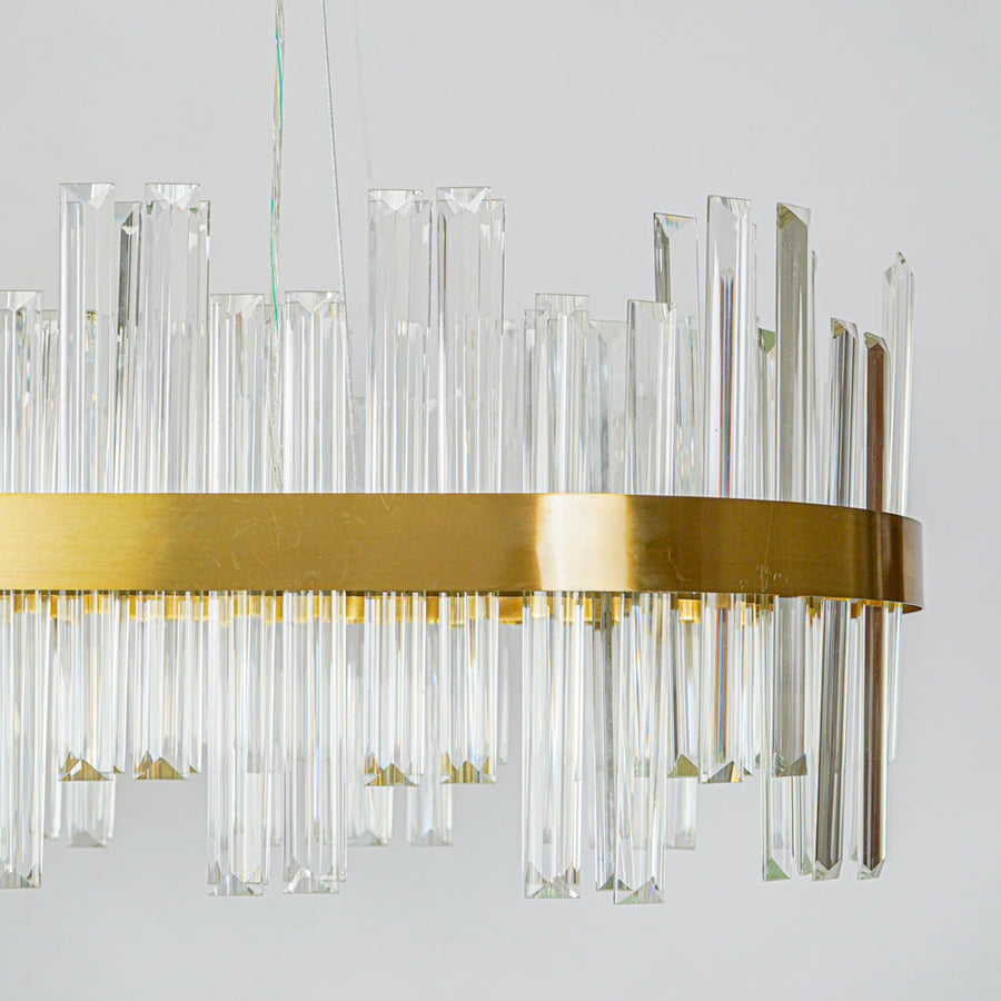 Close up crystal wall light with gold metal frame and structured glass elements mounted on white wall background for premium home decor lighting.