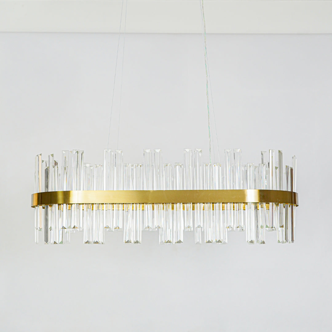 Contemporary gold metal wall sconce with clear glass rod design fixed on minimal white wall background ideal for modern decorative lighting setup.