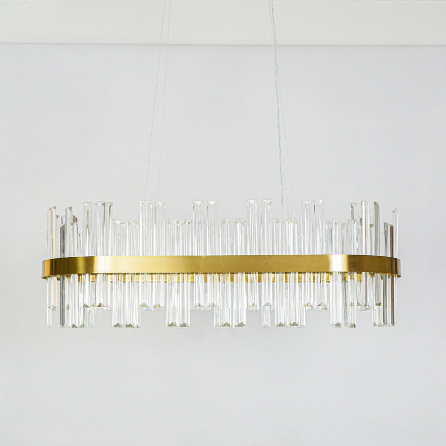 Contemporary gold metal wall sconce with clear glass rod design fixed on minimal white wall background ideal for modern decorative lighting setup.