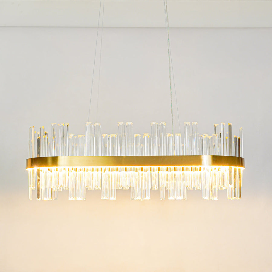 Minimal long crystal wall light with gold metal base and transparent glass rods mounted on clean white wall background for modern ambient lighting.
