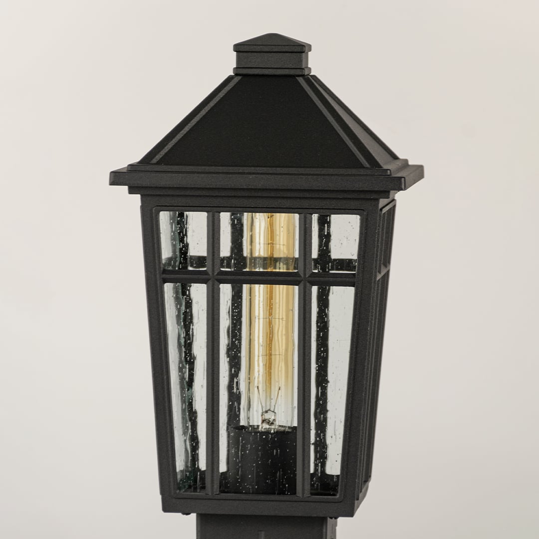 Black outdoor lantern Closeup seeded glass Light On showing the warm ambient glow and decorative pebbled glass panels detail.