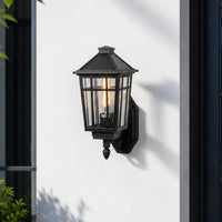 Black metal outdoor wall lantern with clear glass for porch entrance balcony and exterior walls with warm lighting.