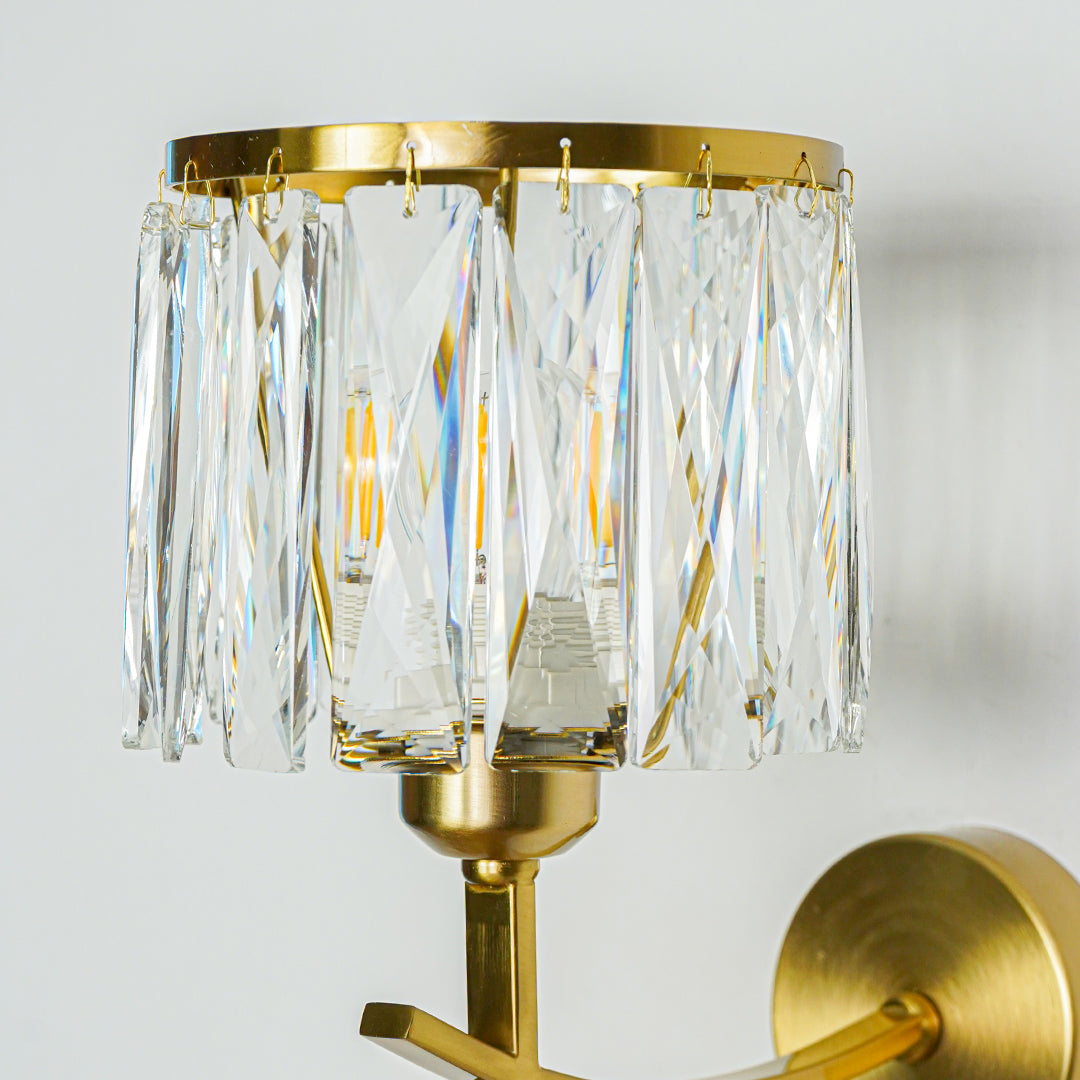 Close view of gold wall sconce with layered crystal glass pieces creating elegant light reflection perfect for premium interior lighting design.