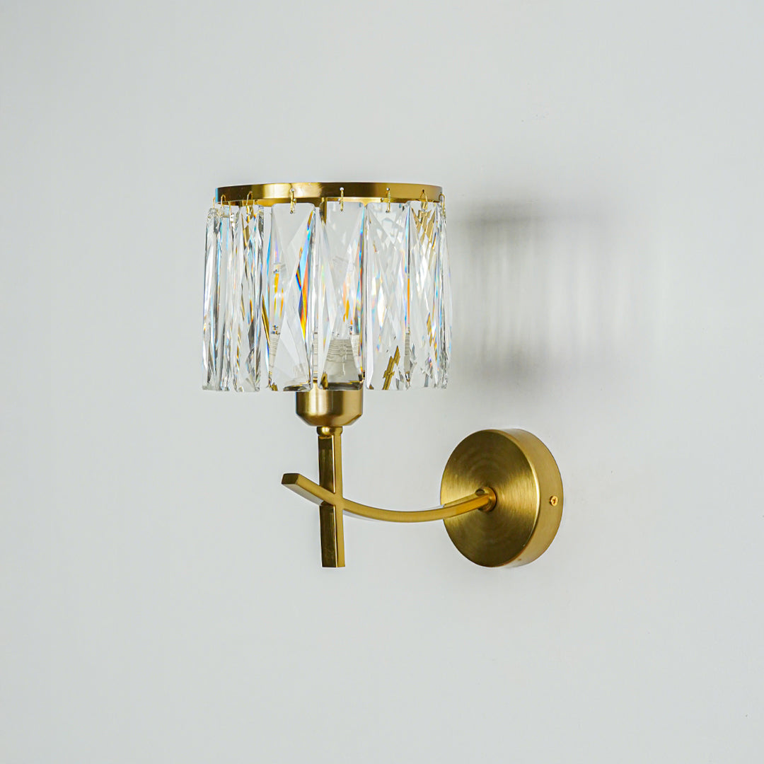 Gold wall light with crystal glass shade mounted on neutral wall background ideal for luxury bedroom or living room decor lighting.
