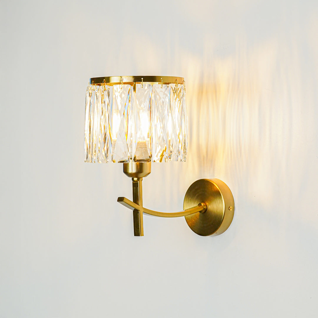Luxury gold wall sconce with crystal glass shade casting warm reflections on textured wall background ideal for upscale home decor lighting.

