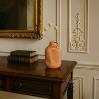 Matte beige ceramic vase with sculptural curved shape styled on table adds modern minimalist elegance to home decor.