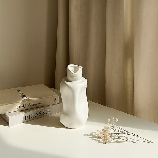 Elegant white ceramic sculptural vase styled in a soft minimal setting adding modern artistic decor to contemporary interiors.