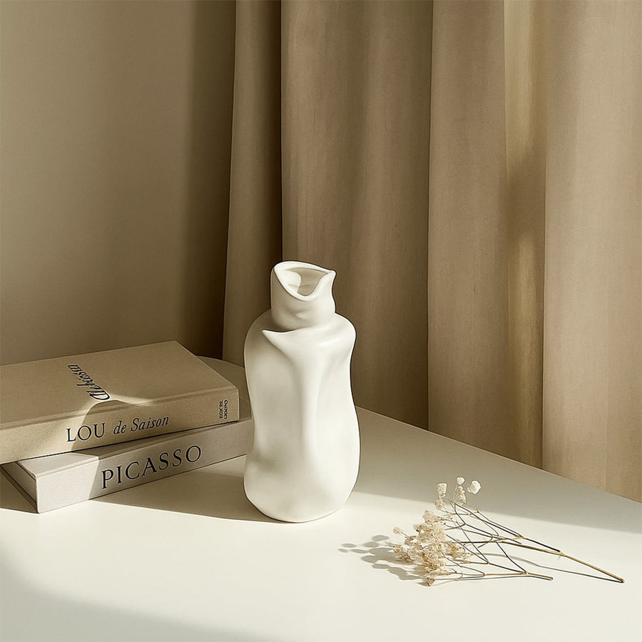 Elegant white ceramic sculptural vase styled in a soft minimal setting adding modern artistic decor to contemporary interiors.