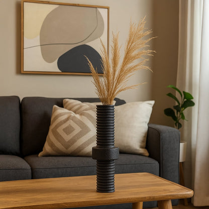 Black ribbed metal vase with matte finish standing on white background showcasing industrial home decor elegance.