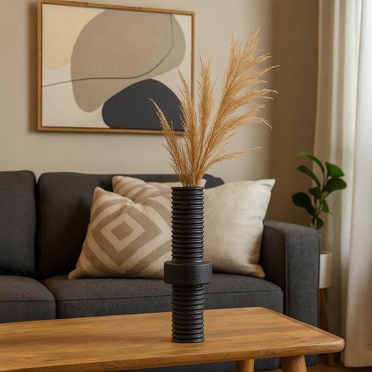 Black ribbed metal vase with matte finish standing on white background showcasing industrial home decor elegance.