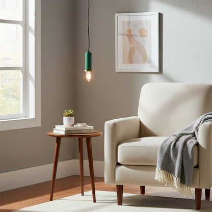 Green metal pendant light hanging near an accent chair creating warm ambient lighting in a modern living room corner space.