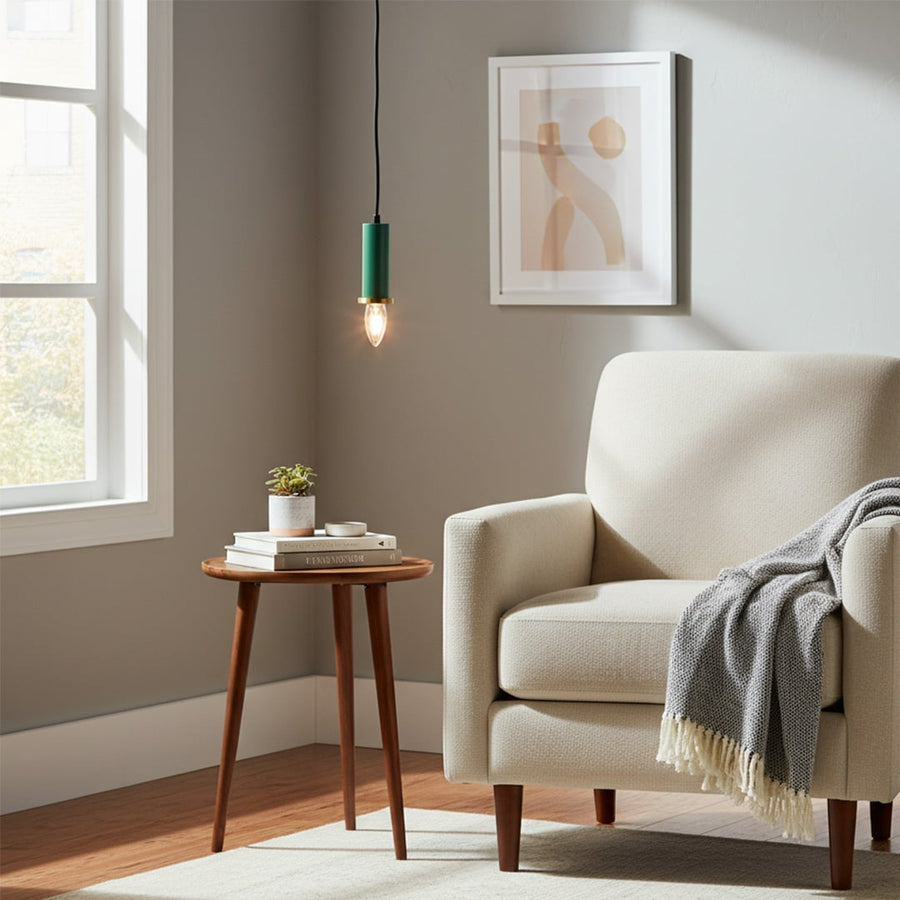 Green metal pendant light hanging near an accent chair creating warm ambient lighting in a modern living room corner space.