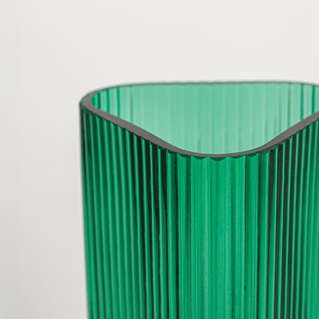 Close up view green ribbed glass vase showing vertical texture glossy finish luxury decorative glass accent for shelf styling home.
