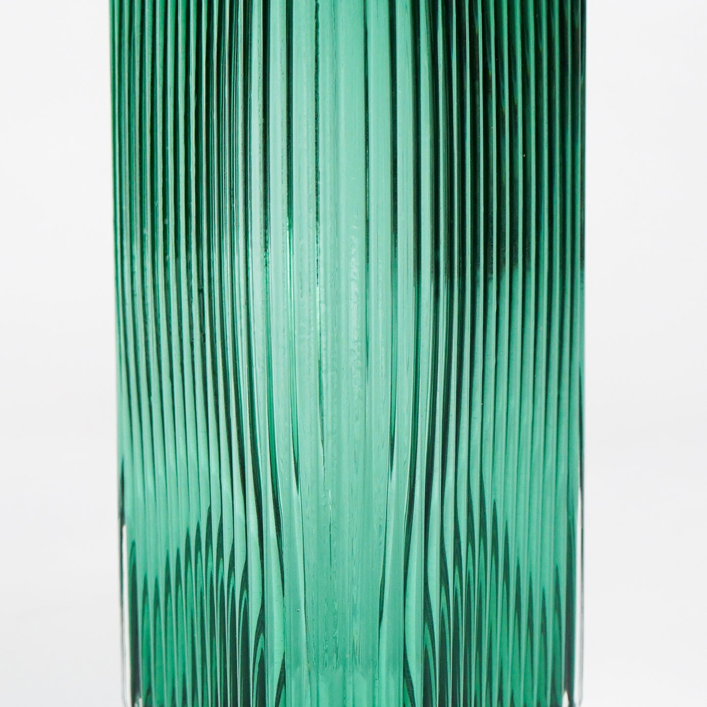 Closeup image of long green luxury glass vase for elegant tabletop decor styling highlighting smooth reflective glass finish.